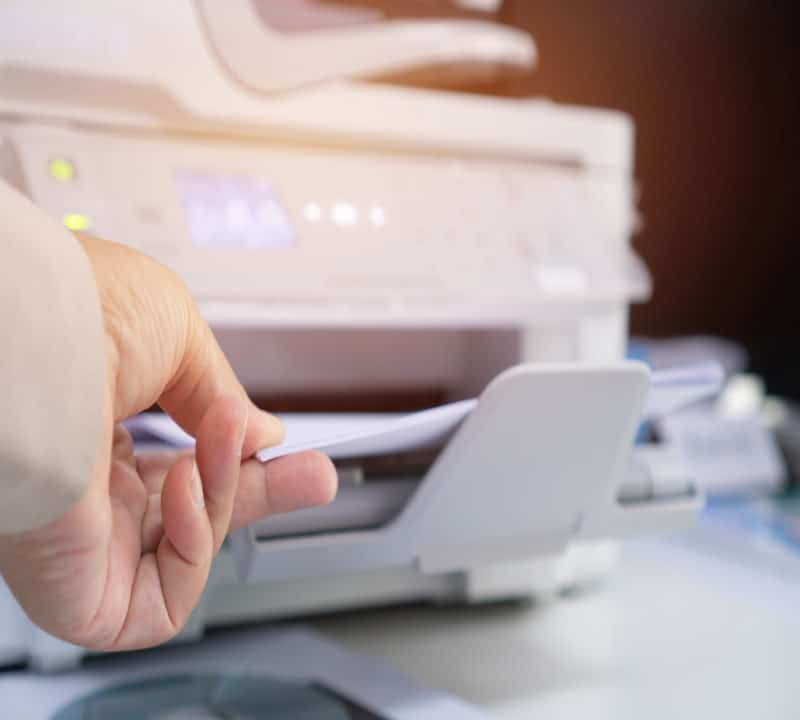 Hand taking paper from a printer tray