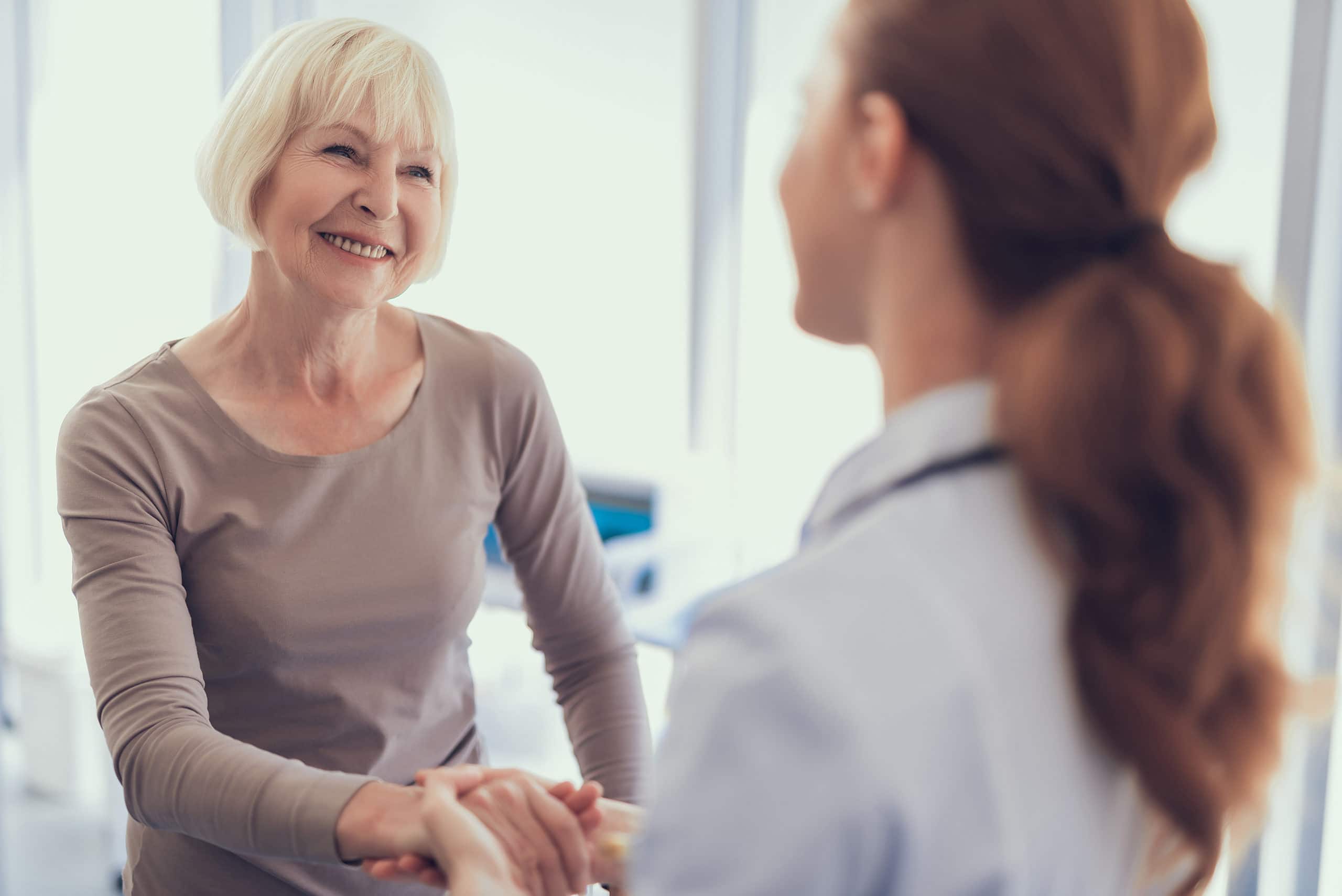 Smiling older patient holding hands with a healthcare provider