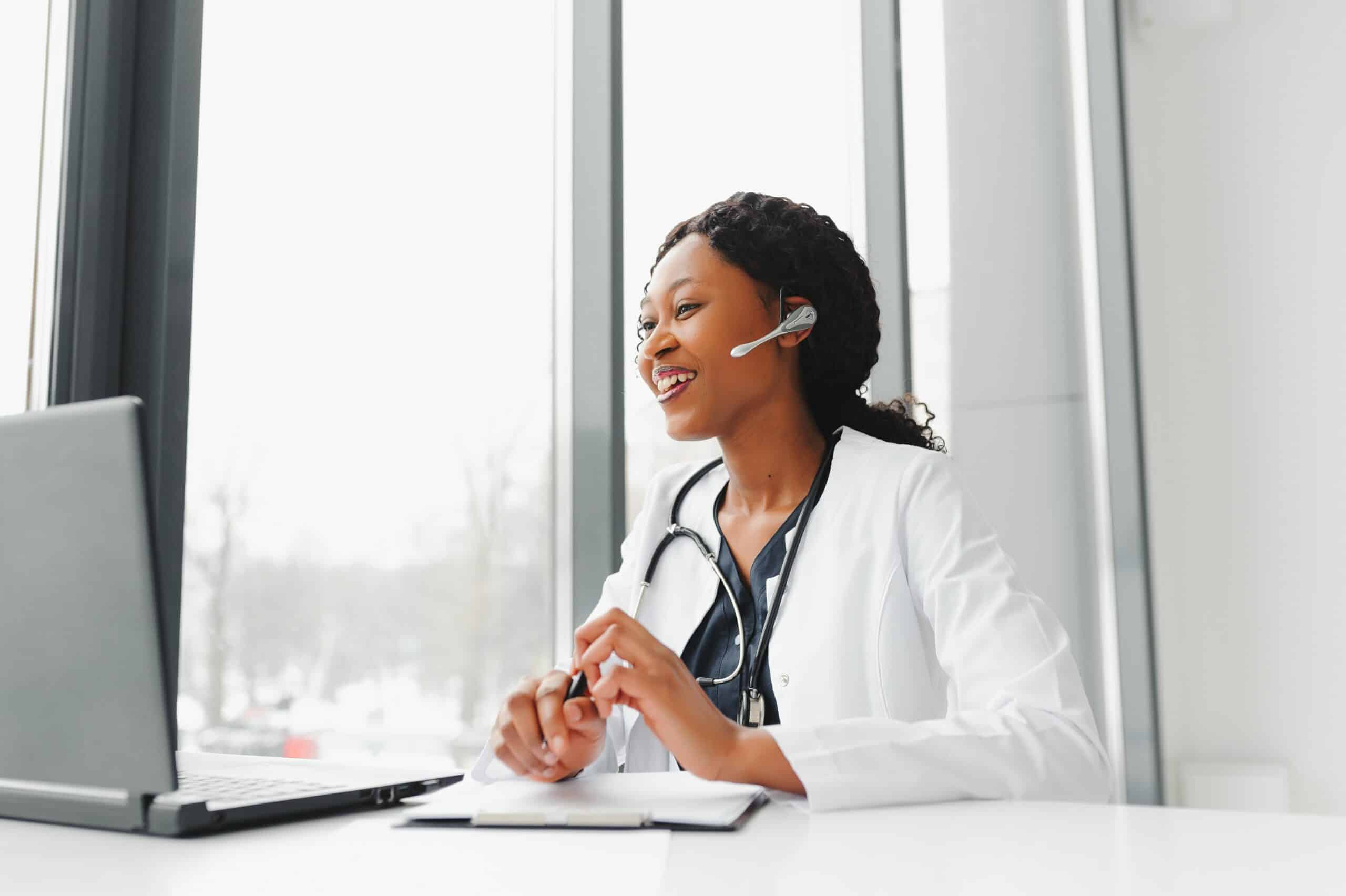 Smiling healthcare worker wearing a headset at a laptop