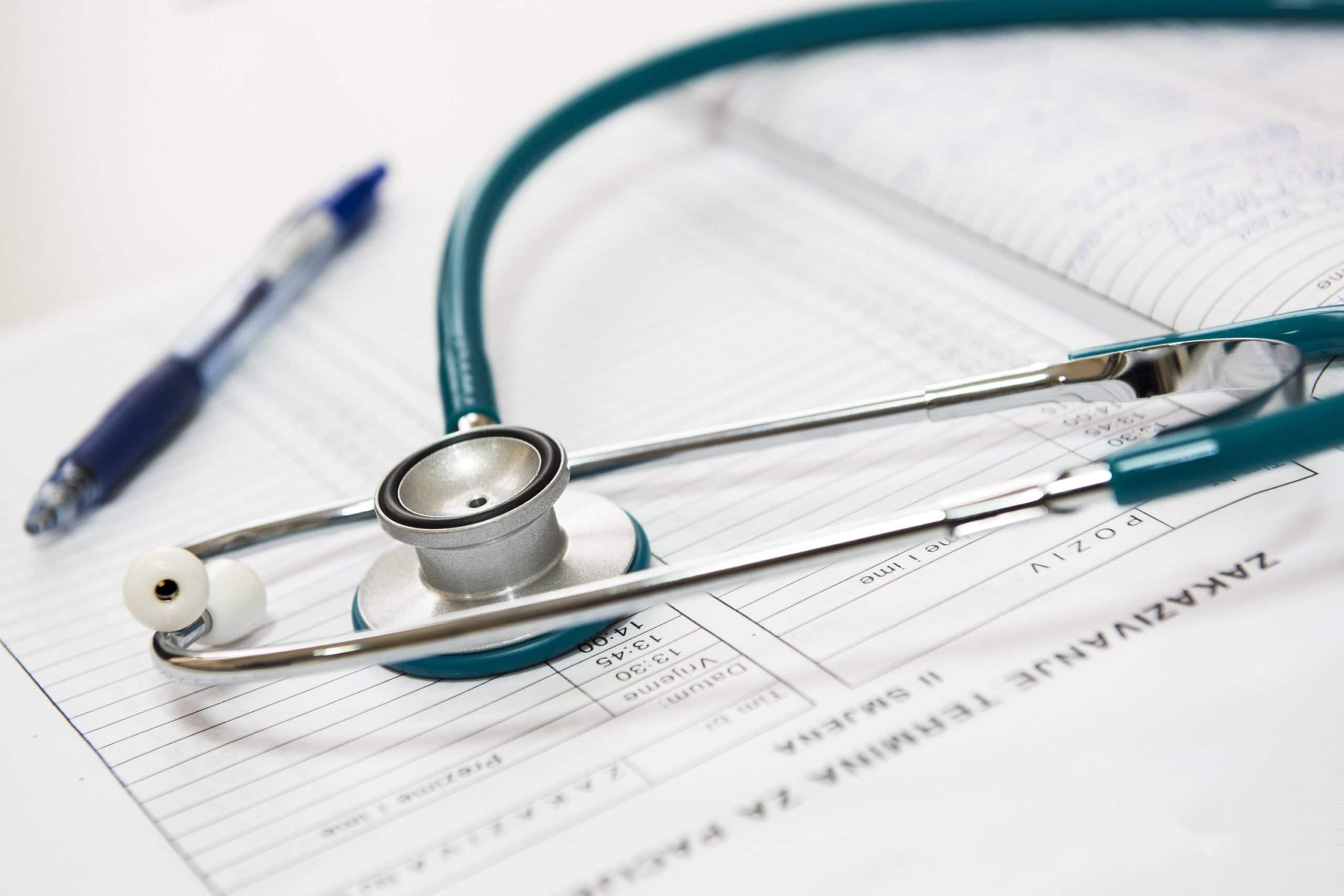 Stethoscope and pen resting on medical appointment forms
