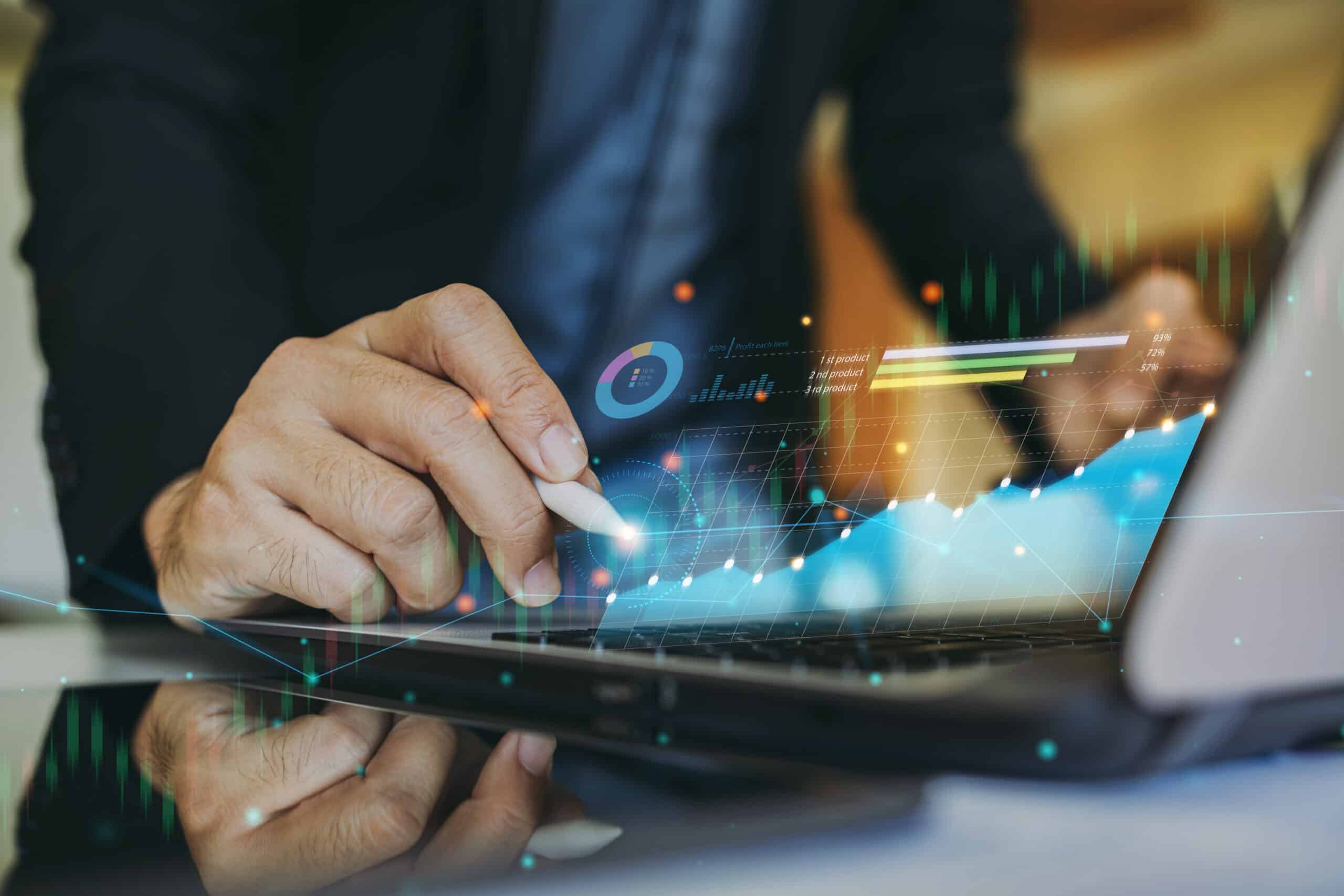 Hand using a stylus on a laptop with glowing growth charts