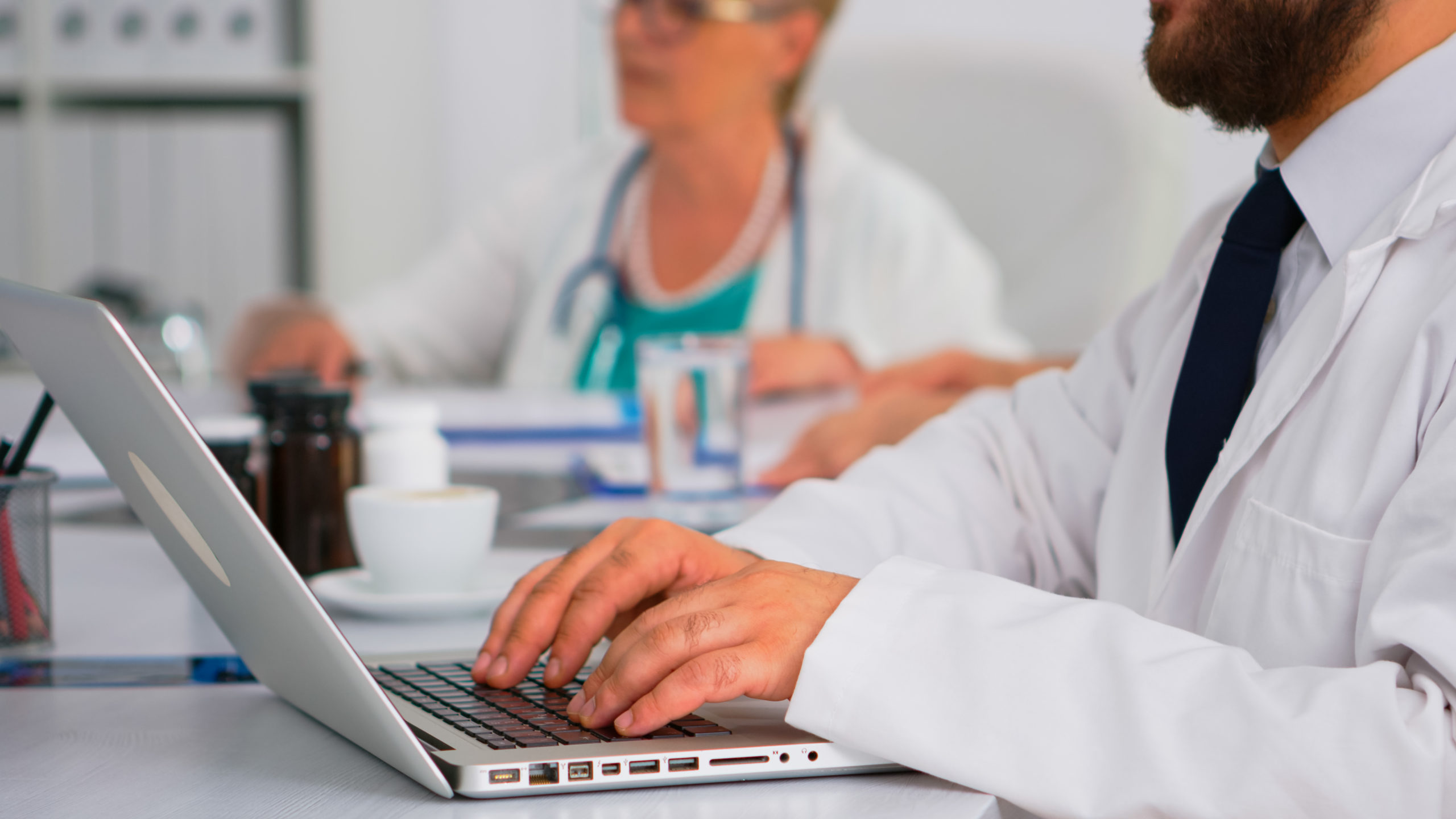 Doctor typing on a laptop while a colleague sits nearby