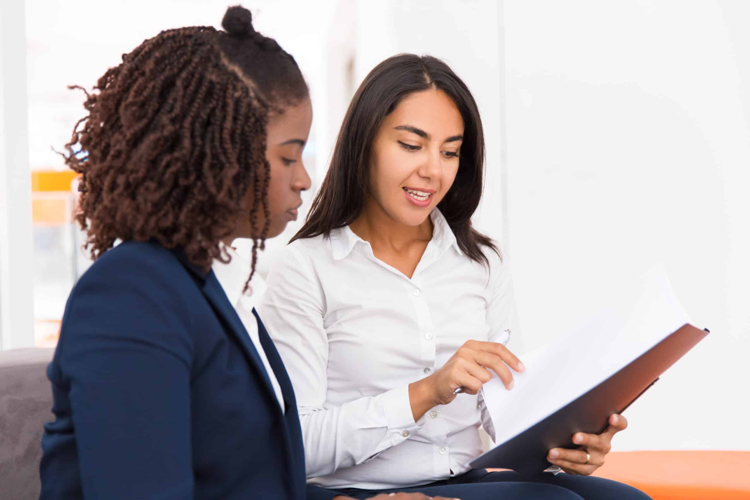 Two professionals reviewing a document on a clipboard together