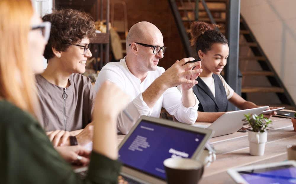 Colleagues smiling and working together around a table with laptops
