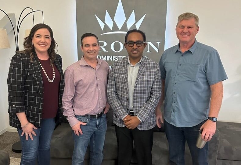 Four people posing together in front of a Crown Administrators sign