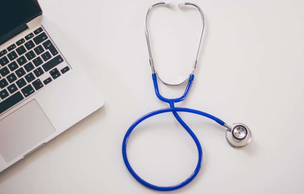 Stethoscope on a desk beside a laptop