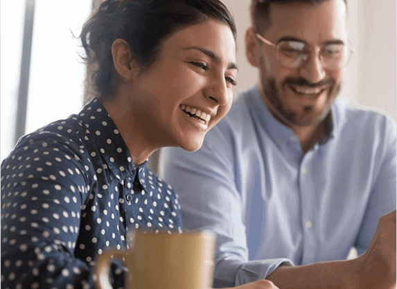 Two colleagues laughing together while looking at a screen