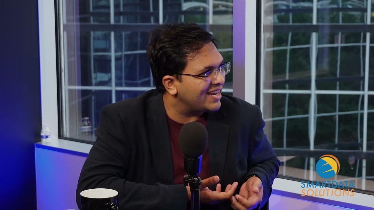 Speaker seated at a microphone in a Smart Data Solutions video interview
