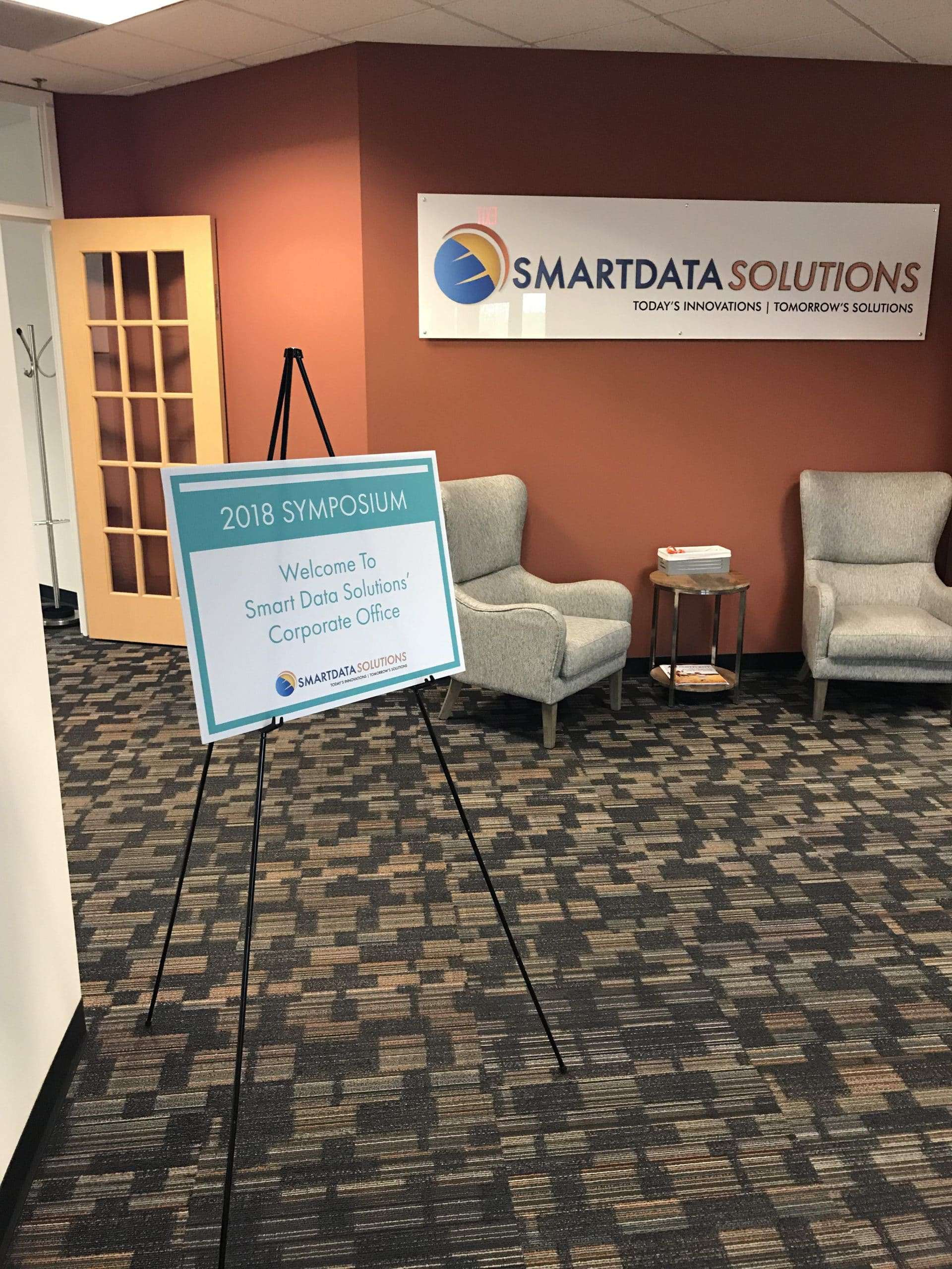 Smart Data Solutions corporate office lobby with a 2018 Symposium welcome sign on an easel
