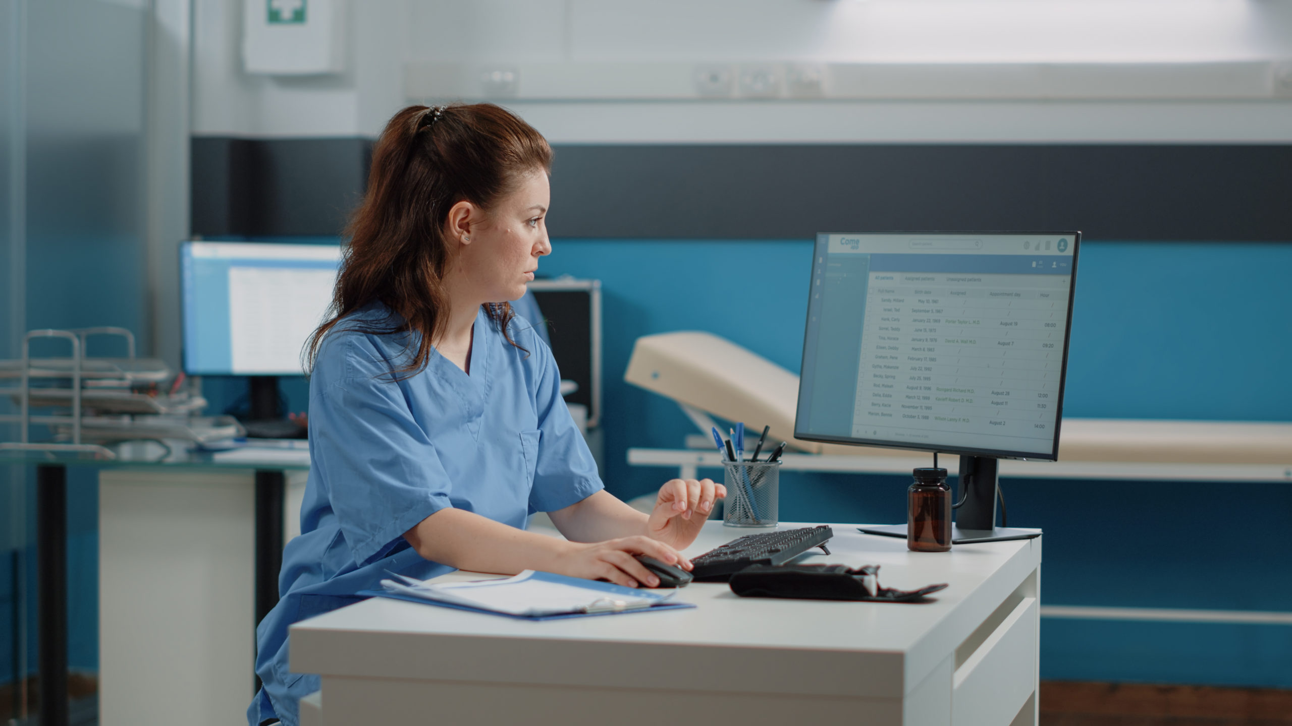 Medical assistant at a computer reviewing patient appointment records