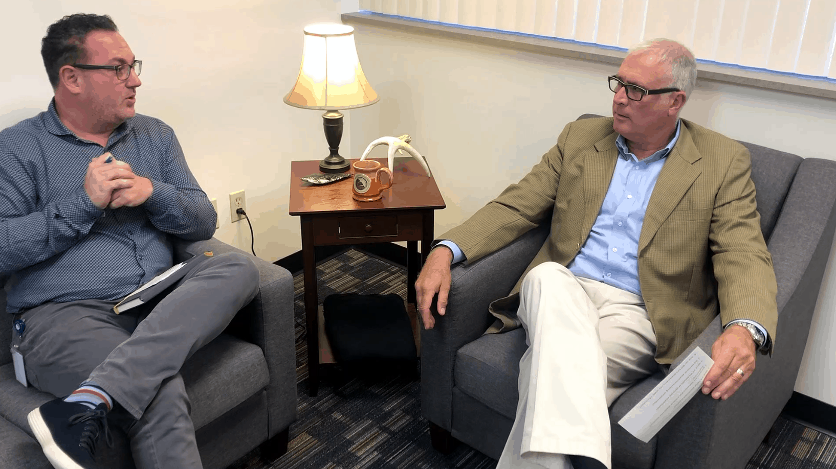 Two men in conversation seated in armchairs
