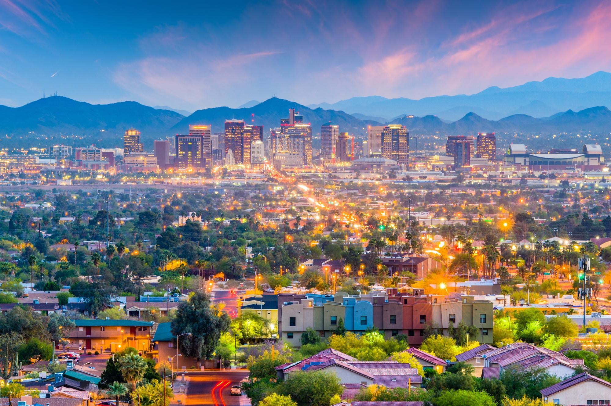 Evening city skyline with mountains in the distance and glowing streets