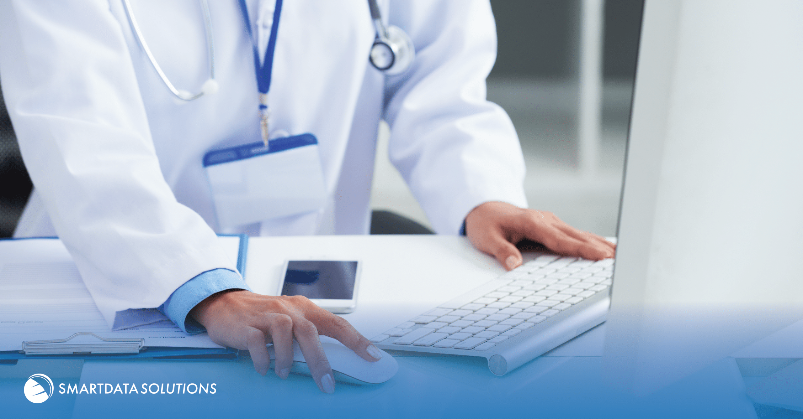 Doctor in a white coat using a computer mouse and keyboard, Smart Data Solutions branded image
