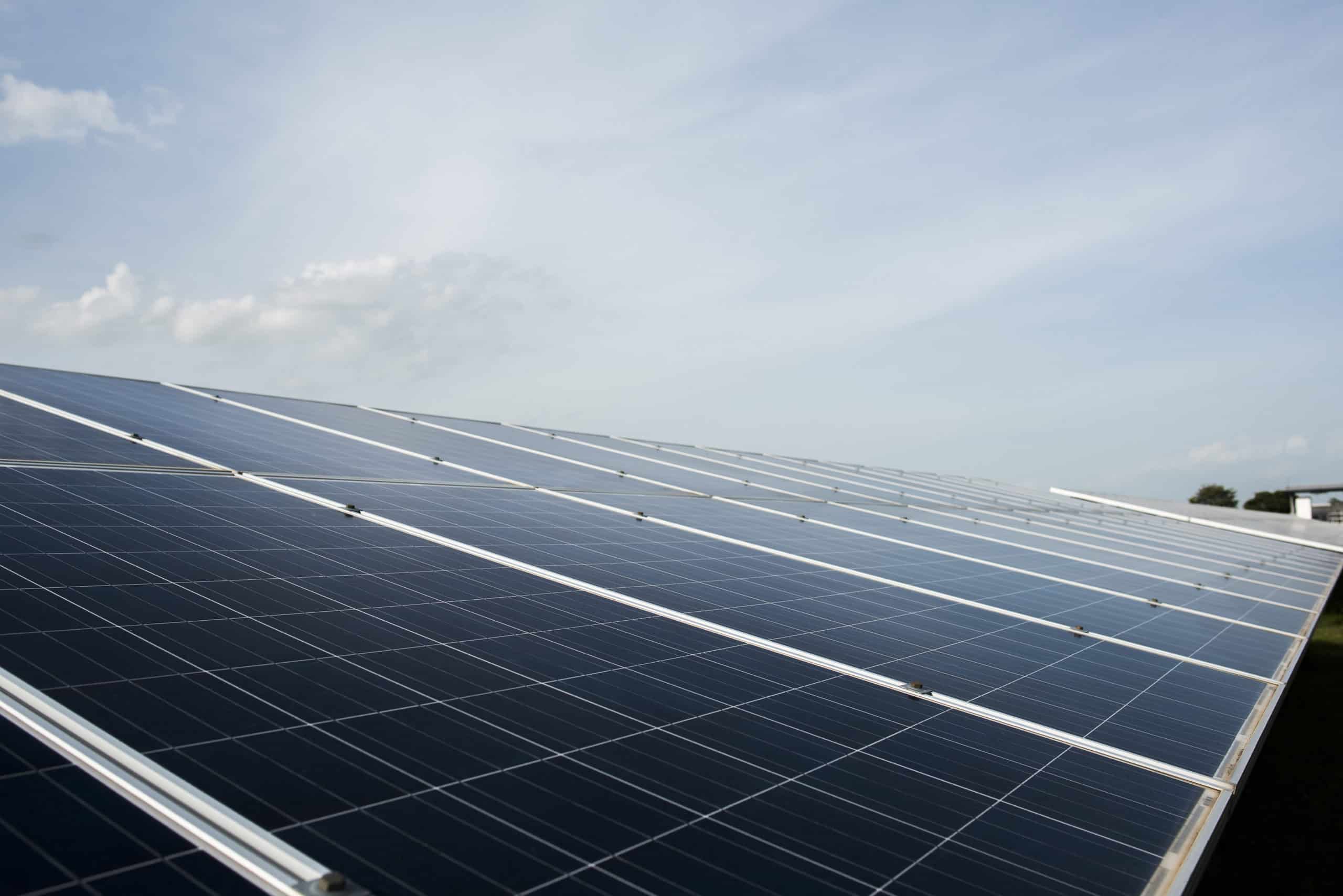 Rows of solar panels under a partly cloudy sky