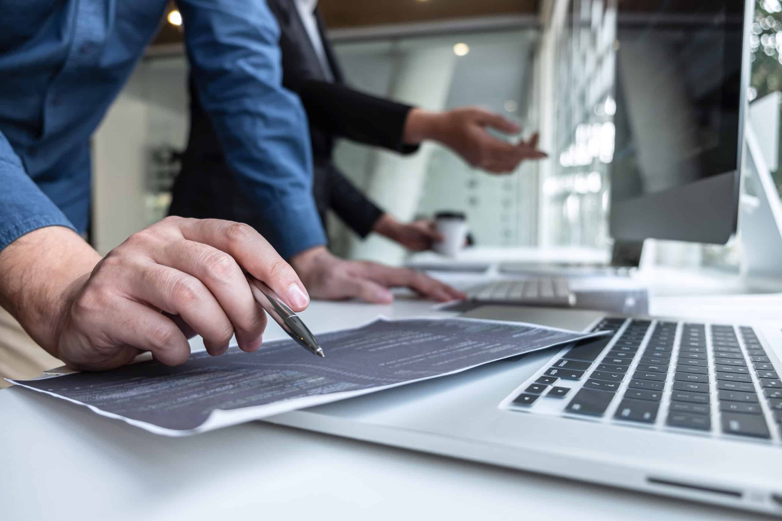 Colleagues reviewing a printed document beside a laptop in an office
