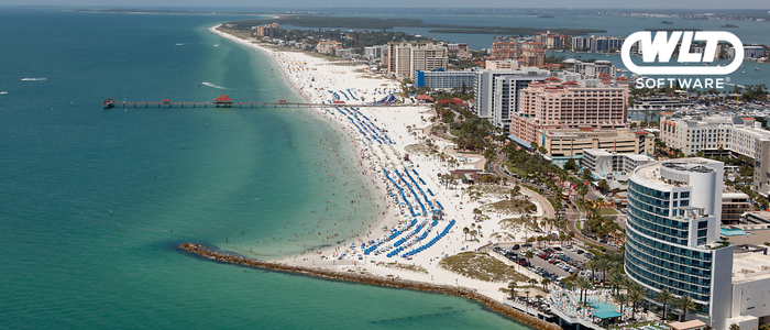 WLT Software logo over an aerial view of a beach and coastal resort