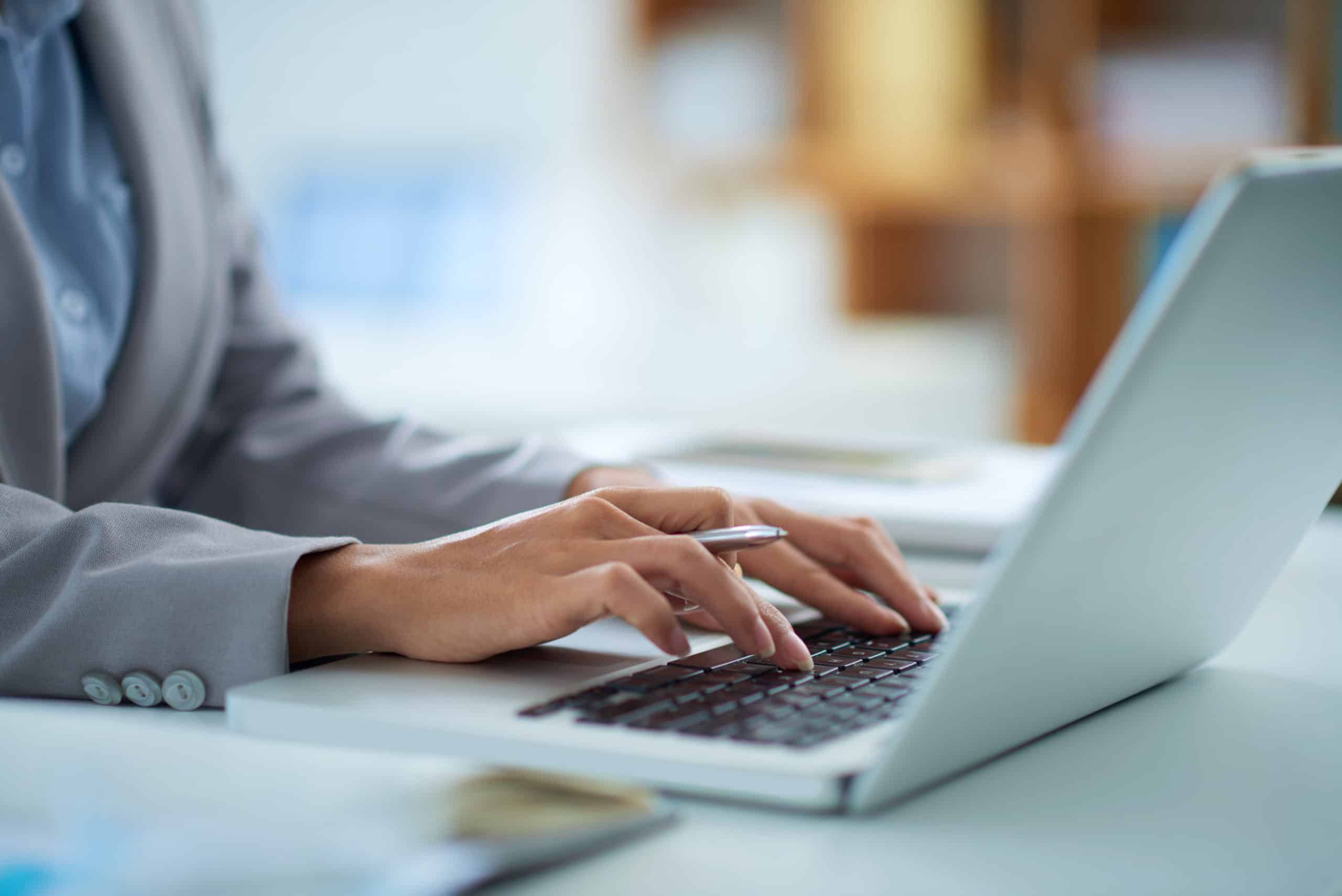 Hands typing on a laptop at a desk
